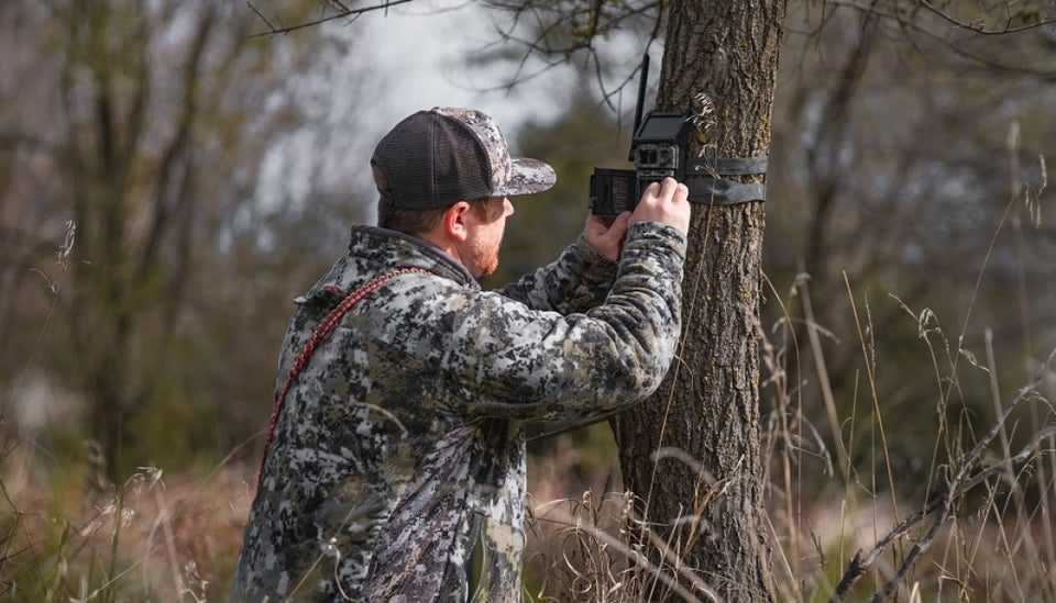 Hunter checking trail camera in wooded area
